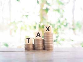 Wooden blocks with the word TAX and stack of coins, The concept of paying tax for every thing. photo