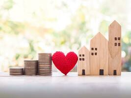 Miniature house, red heart and stack of coins. Investment property concept. photo