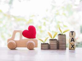 plantas creciente arriba en apilar de monedas con de madera juguete auto, de madera bloques con el palabra impuesto. el concepto de pago impuesto para coche. foto