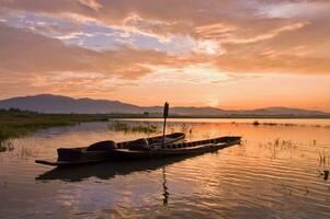 pescador barco con amanecer cielo en el lago foto