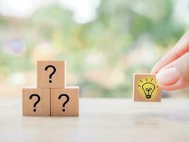 Close up hand arranging wooden block with light bulb and wooden block with question mark for leadership, creative, idea, innovation concept. photo