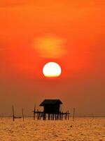 silueta del pescador choza con durante puesta de sol foto