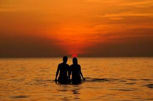 Silhouette of couple in the sea at sunset photo