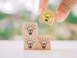 Close up hand arranging wooden block with light bulb for leadership, creative, idea, innovation concept. photo