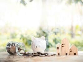 Piggy bank on stack of coins and miniature house. The saving concept for house and property. photo