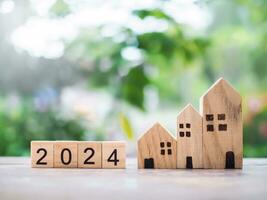 de madera bloquear con 2024 y miniatura casa. el concepto de propiedad inversión, casa hipoteca, real estste. foto
