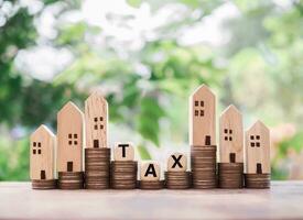 Miniature house, wooden blocks with the word TAX and stack of coins. The concept of paying tax for house and property. photo