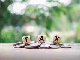 Wooden blocks with the word TAX and stack of coins, The concept of paying tax for every thing. photo