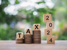 Wooden blocks with the word TAX 2024 on stack of coins. The concept of prepare to pay tax in new year 2024 photo
