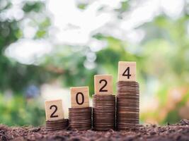 Wooden black with number 2024 on stack of coins. The concept for saving money, business financial plan and investment in new year 2024 photo