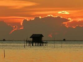 silueta del pescador choza con durante puesta de sol foto