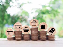 Wooden block with shopping cart icons on stack of coins. The concept of saving money for shopping. photo