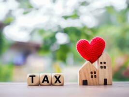 Wooden blocks with the word TAX and miniature house. The concept of paying tax for house and property. Property taxes. photo