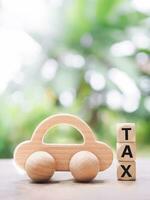 Wooden toy car ans Wooden blocks with the word TAX. The concept of paying tax for car. photo