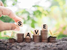 Close up hand arranging wooden blocks with the word SAVE on stack of coins, The concept of save money for prepare in the future. photo