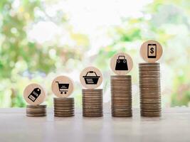 Wooden block with shopping cart icons on stack of coins. The concept of saving money for shopping. photo