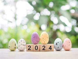Easter eggs and wooden block with number 2024 for EASTER DAY in new year 2024 concept. photo