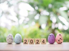 Easter eggs and wooden block with number 2024 for EASTER DAY in new year 2024 concept. photo