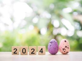 Easter eggs and wooden block with number 2024 for EASTER DAY in new year 2024 concept. photo