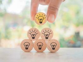 Close up hand arranging wooden block with light bulb for leadership, creative, idea, innovation concept. photo