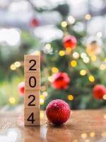 Wooden block number 2024 and red ball with Christmas light bokeh background. Merry Christmas and Happy New Year 2024 photo