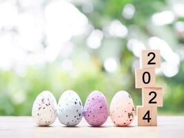 Easter eggs and wooden block with number 2024 for EASTER DAY in new year 2024 concept. photo
