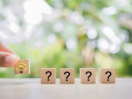 Close up hand arranging wooden block with light bulb and wooden block with question mark for leadership, creative, idea, innovation concept. photo