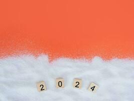 Wooden block with number 2024 and white sand on orange background. Top view with copy space of summer background. The concept for summer of new year 2024 photo