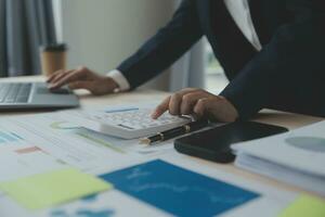 Close up Business woman using calculator and laptop for do math finance on wooden desk, tax, accounting, statistics and analytical research concept photo