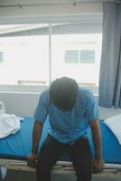 Depressed senior man sitting on the hospital bed alone at night, he feels lonely and abandoned photo