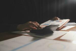 Close up businessman hand using calculator and working with laptop calculate about finance accounting at coffeeshop outdor.finance accounting concept photo