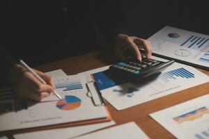 Close up businessman hand using calculator and working with laptop calculate about finance accounting at coffeeshop outdor.finance accounting concept photo