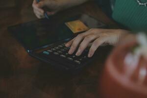 Close up businessman hand using calculator and working with laptop calculate about finance accounting at coffeeshop outdor.finance accounting concept photo