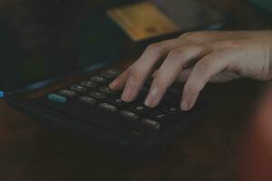 Close up businessman hand using calculator and working with laptop calculate about finance accounting at coffeeshop outdor.finance accounting concept photo