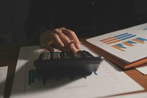 Close up businessman hand using calculator and working with laptop calculate about finance accounting at coffeeshop outdor.finance accounting concept photo