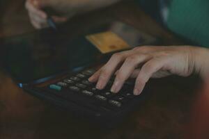 Close up businessman hand using calculator and working with laptop calculate about finance accounting at coffeeshop outdor.finance accounting concept photo