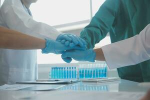 Mature doctors and young nurses stacking hands together at hospital. Close up hands of medical team stacking hands. Group of successful medical doctors and nurses stack of hands. photo