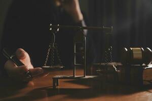 Business and lawyers discussing contract papers with brass scale on desk in office. Law, legal services, advice, justice and law concept picture with film grain effect photo