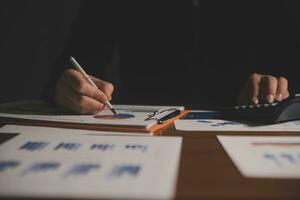 Close up businessman hand using calculator and working with laptop calculate about finance accounting at coffeeshop outdor.finance accounting concept photo