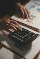 Close up businessman hand using calculator and working with laptop calculate about finance accounting at coffeeshop outdor.finance accounting concept photo