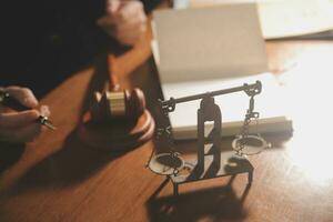 Business and lawyers discussing contract papers with brass scale on desk in office. Law, legal services, advice, justice and law concept picture with film grain effect photo