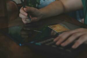 Close up businessman hand using calculator and working with laptop calculate about finance accounting at coffeeshop outdor.finance accounting concept photo