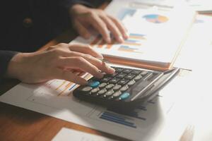 Close up businessman hand using calculator and working with laptop calculate about finance accounting at coffeeshop outdor.finance accounting concept photo