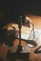 Business and lawyers discussing contract papers with brass scale on desk in office. Law, legal services, advice, justice and law concept picture with film grain effect photo