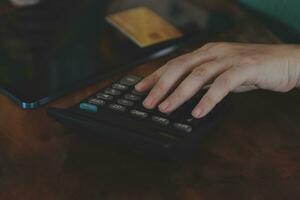 Close up businessman hand using calculator and working with laptop calculate about finance accounting at coffeeshop outdor.finance accounting concept photo