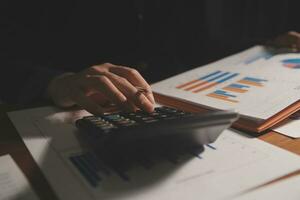 Close up businessman hand using calculator and working with laptop calculate about finance accounting at coffeeshop outdor.finance accounting concept photo