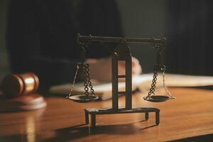 Business and lawyers discussing contract papers with brass scale on desk in office. Law, legal services, advice, justice and law concept picture with film grain effect photo