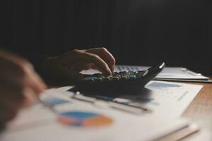 Close up businessman hand using calculator and working with laptop calculate about finance accounting at coffeeshop outdor.finance accounting concept photo