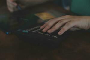 Close up businessman hand using calculator and working with laptop calculate about finance accounting at coffeeshop outdor.finance accounting concept photo