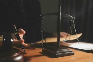 Business and lawyers discussing contract papers with brass scale on desk in office. Law, legal services, advice, justice and law concept picture with film grain effect photo